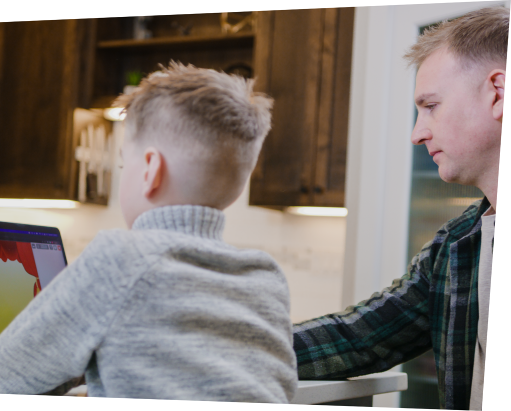 Child using Funnix program sitting next to Father in kitchen.